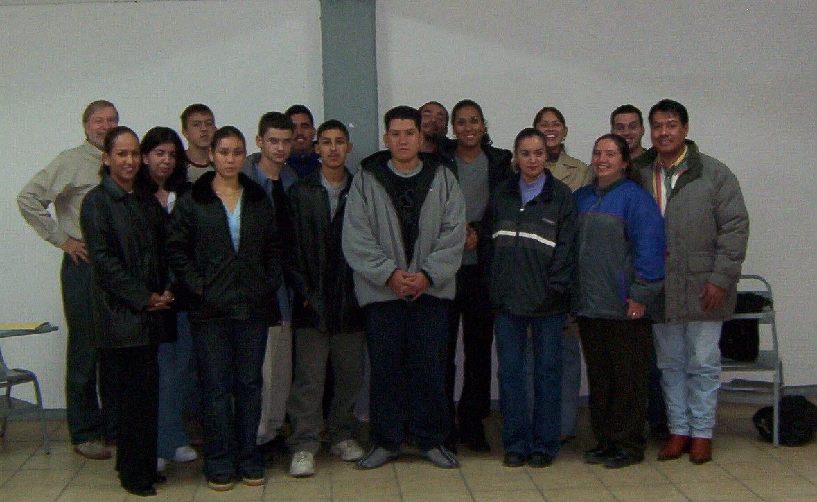A large group of students and adults in winter coats posed together indoors